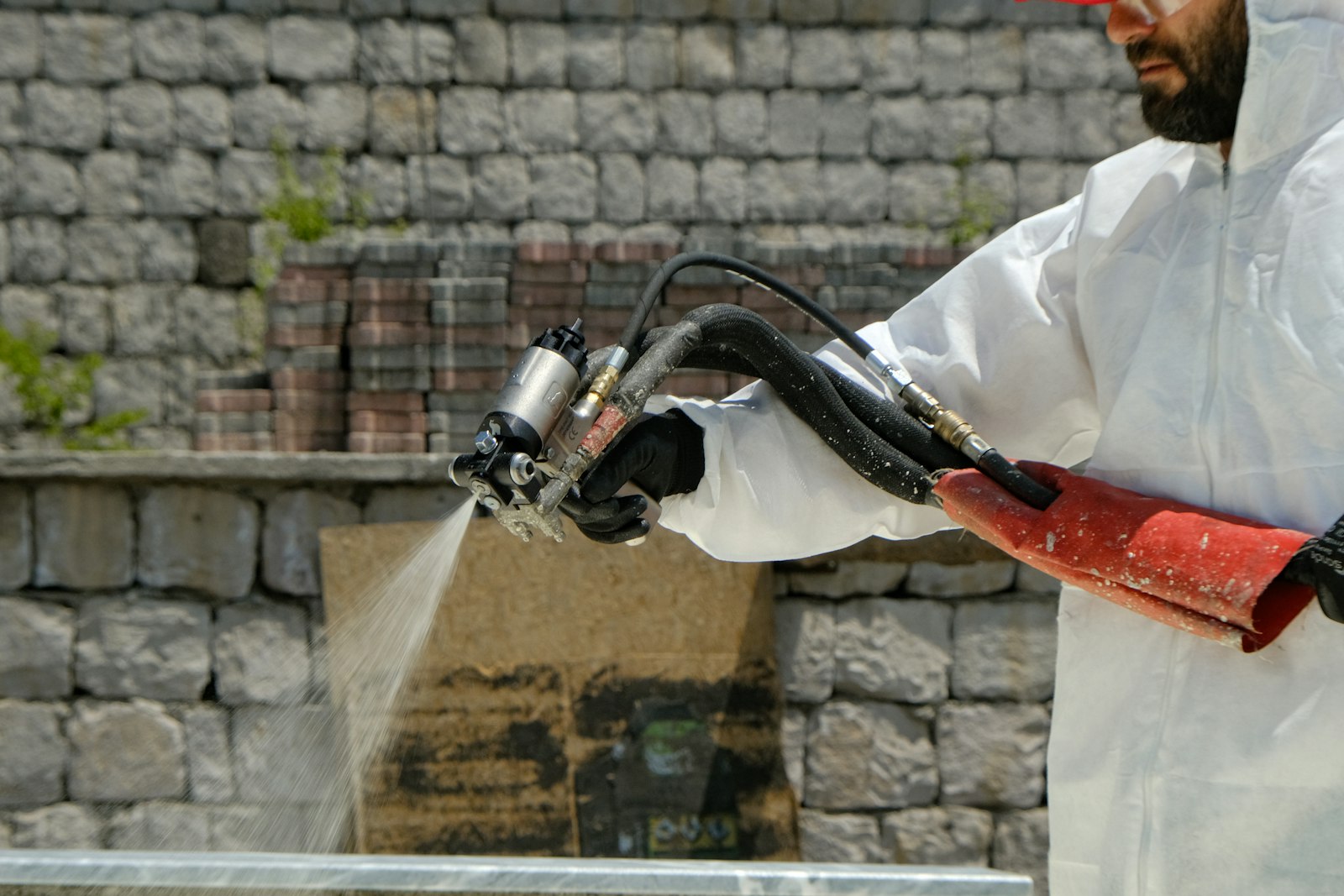 Technician applying treatment along a stone foundation
